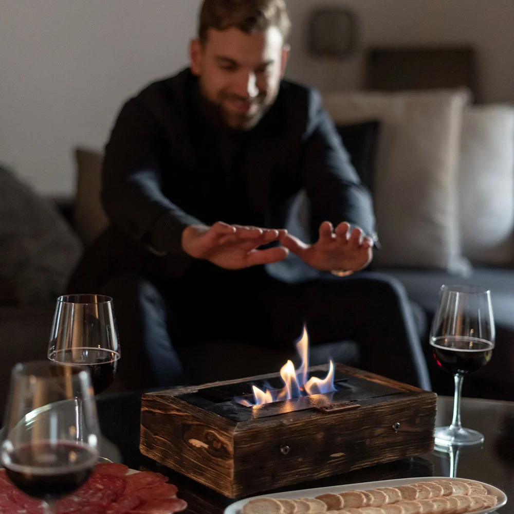 Hombre calentando sus manos en la chimenea de bioetanol