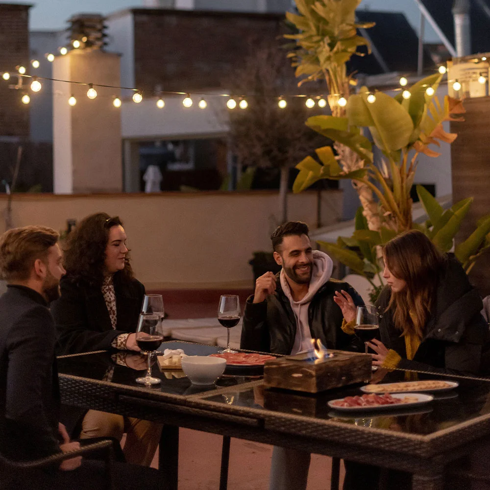 Amigos platicando con chimenea de bioetanol en terraza